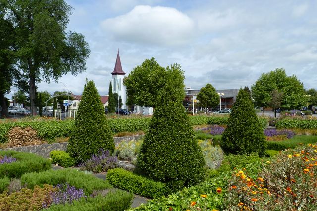 Gardens in central Masterton with a white church spire and town buildings behind.